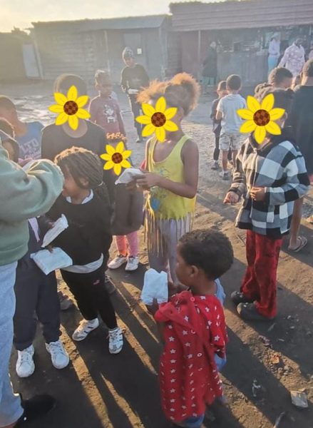 Children in line, sandwiches in hand. Faces hidden to safeguard young recipients.