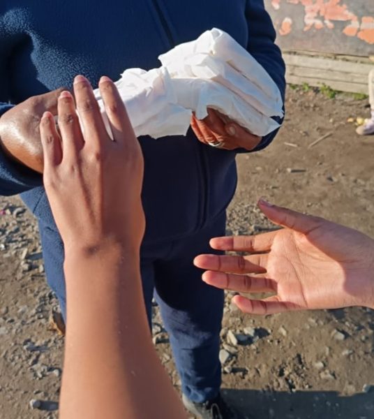Hands meet — a fresh sandwich passed across the divide.